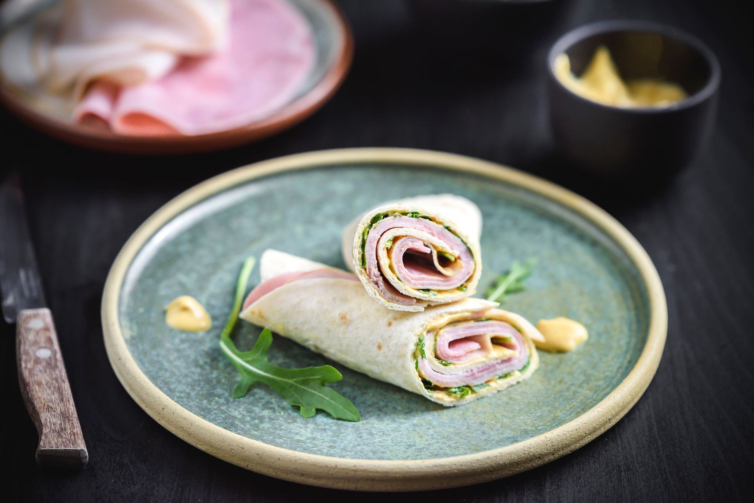 A low-calorie ham and turkey wrap cut in half and resting on a plate