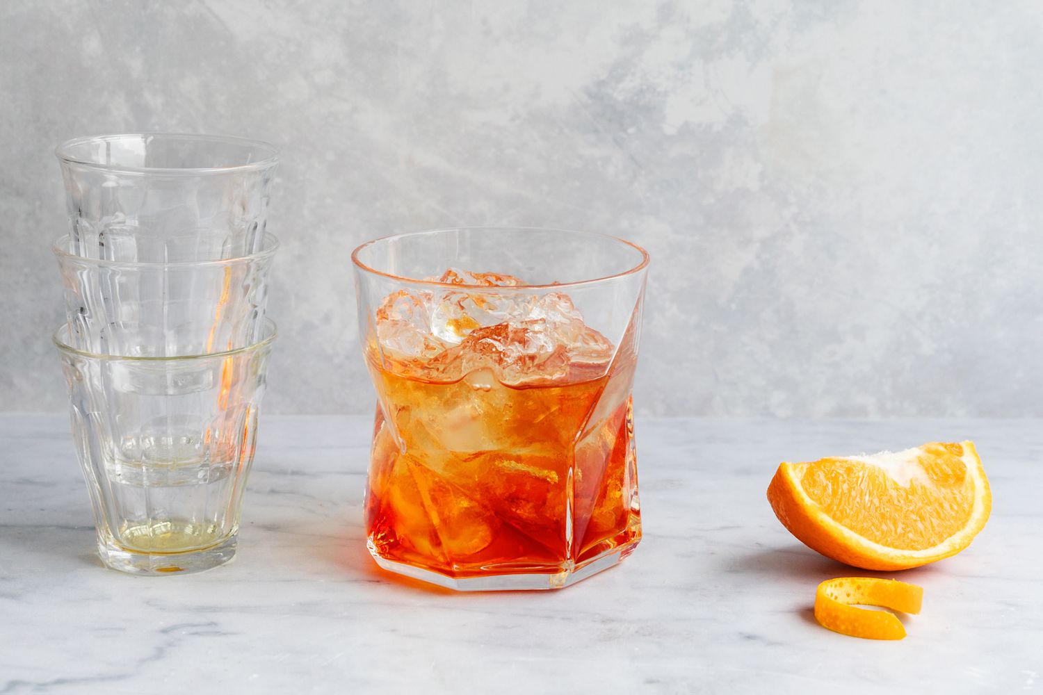 Negroni ingredients in glass with an orange wedge alongside