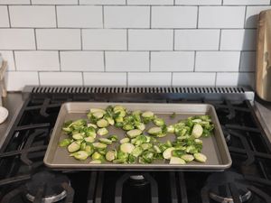 OXO Non-Stick Pro Half Sheet Pan filled with cut Brussels sprouts displayed on gas stovetop with nearby white subway tile