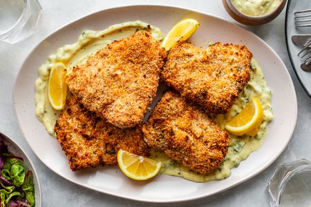 Panko-crusted oven-fried haddock on a plate with orange slices