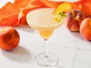 Frozen peach margarita surrounded by peaches