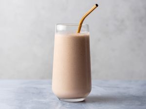 Peanut banana cinnamon smoothie in a glass with a straw