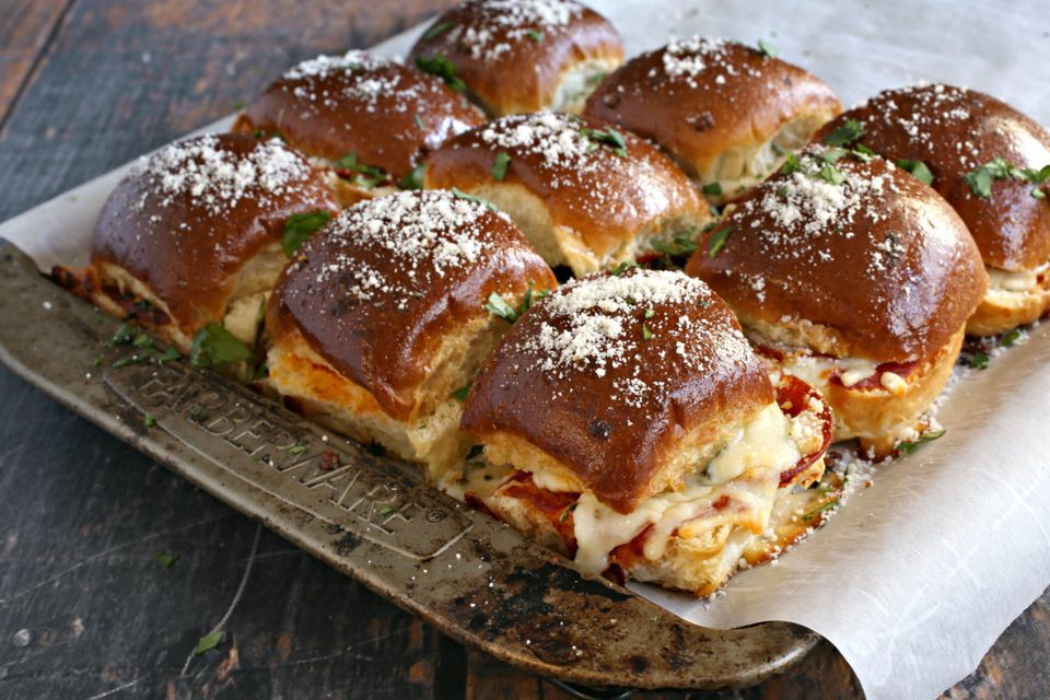 A baking sheet with nine pepperoni pizza sliders next to each other