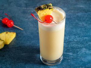 Piña colada cocktail garnished with cherry and pineapple wedge