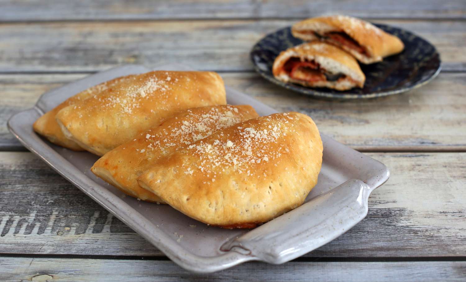 Three easy pizza pockets on a platter with an addition pocket cut in half on a plate in the background