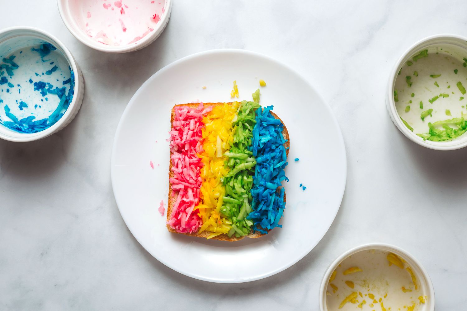 four different colored cheeses arranged in four stripes on a piece of bread