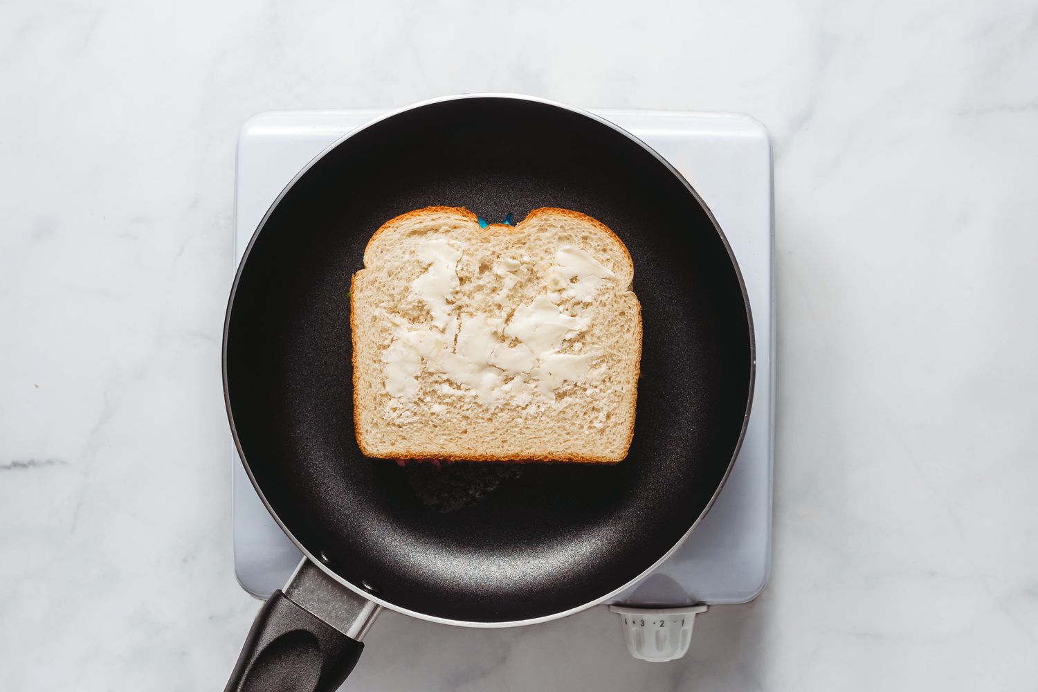 grilled cheese in pan with butter being cooked