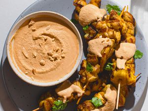 Satay peanut sauce alongside chicken satay on a platter