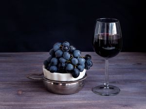 Sangiovese in wine glass, bunch of dark purple grapes