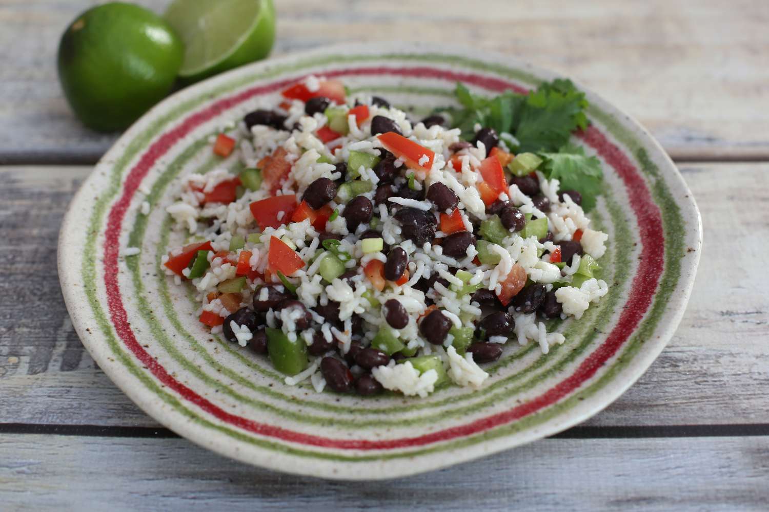 A rice and black bean salad on a white, red, and green plate