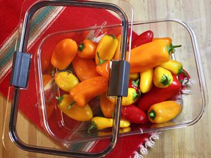 Peppers inside Rubbermaid Brilliance Food Storage Container on a wood surface