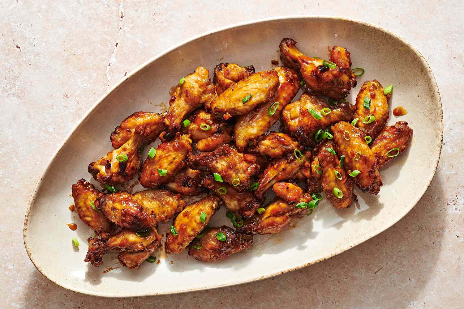 A large platter of air fryer honey garlic wings, garnished with sliced scallions