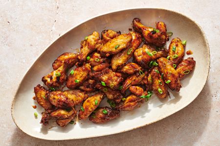 A large platter of air fryer honey garlic wings, garnished with sliced scallions