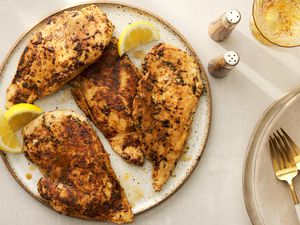 A plate of blackened chicken served with lemon wedges