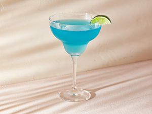 A blue lagoon margarita garnished with a lime wedge