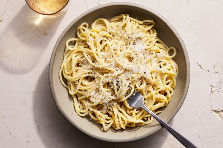 Cacio-e-pepe served in low bowl, topped with Pecorino Romano cheese.