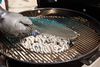 Hand placing grate above charcoals on the Weber Performer Deluxe