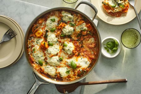 A skillet of chicken sausage and tortellini pasta, garnished with fresh basil leaves