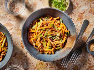 Two bowls of chicken yaki udon, garnished with sesame seeds and sliced scallions