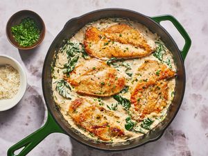 A skillet of chicken Florentine with extra parsley and parmesan cheese served on the side