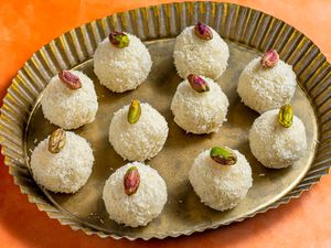 A fluted platter of coconut laddoo, topped with pistachios