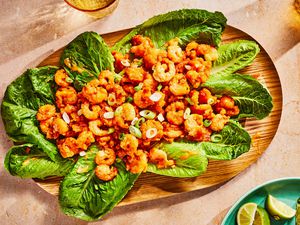 A platter of Bang Bang Shrimp served on lettuce, with a dish of lime wedges