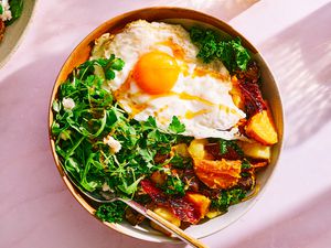 A bowl of First Watch's Million Dollar Harvest Hash, topped with a fried egg and honey