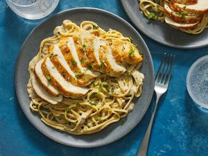 A plate of creamy pasta with sliced chicken on top