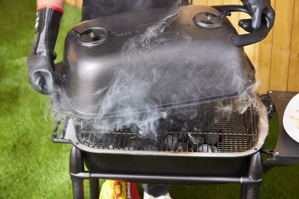 Closeup of a opening the lid on the PK Grills PKGo Camp & Tailgate Grilling System