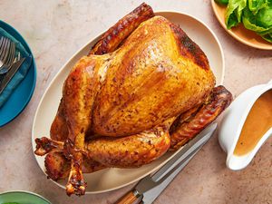 A garlic and scallion-soy sauce whole turkey served on a platter, with gravy and green salad on the side.