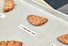 Halved grilled meat patties arranged on a baking sheet