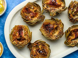 A platter of grilled artichokes served with lemon and aioli