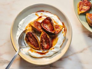 A bowl of yogurt topped with honey-fried figs, with a small bowl of extra honey-fried figs