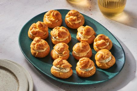 A green platter with Boursin cheese puffs, served with glasses of white wine