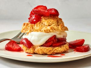 A plate with a strawberry shortcake, topped with extra strawberries