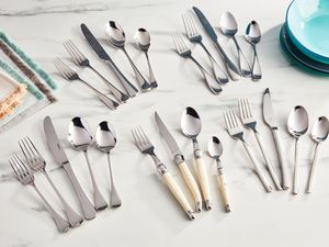 Different types of flatware and silverware sets displayed on a marble table