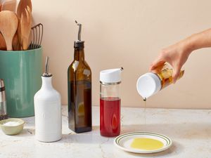 Hand dispensing olive oil next to a display of more of the best olive oil dispensers