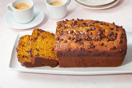 A loaf of sliced pumpkin bread served with coffee