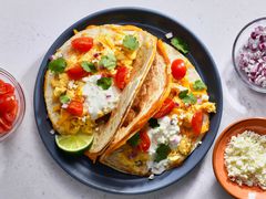 Breakfast quesadilla tacos topped with cilantro, sour cream, and tomoatoes