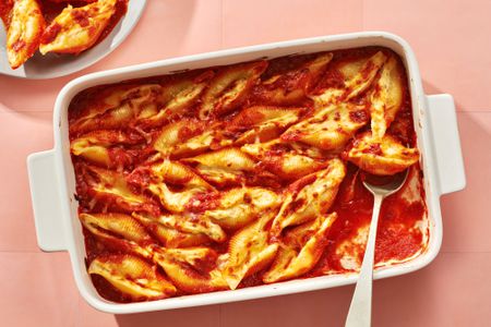 A baking dish of stuffed shells, with a plate of stuffed shells