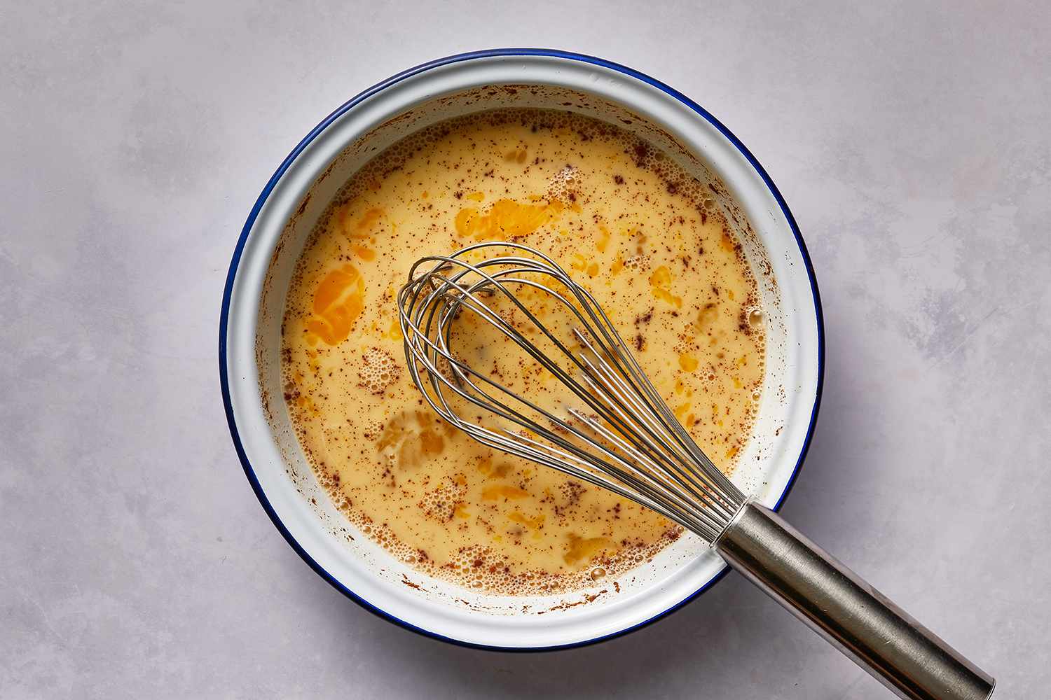 Eggs, milk, sugar, salt, vanilla extract and cinnamon in a bowl with a whisk 