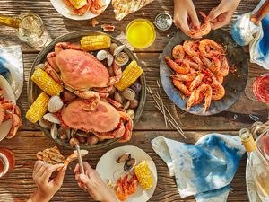 overhead of hands peeling seafood at seafood boil