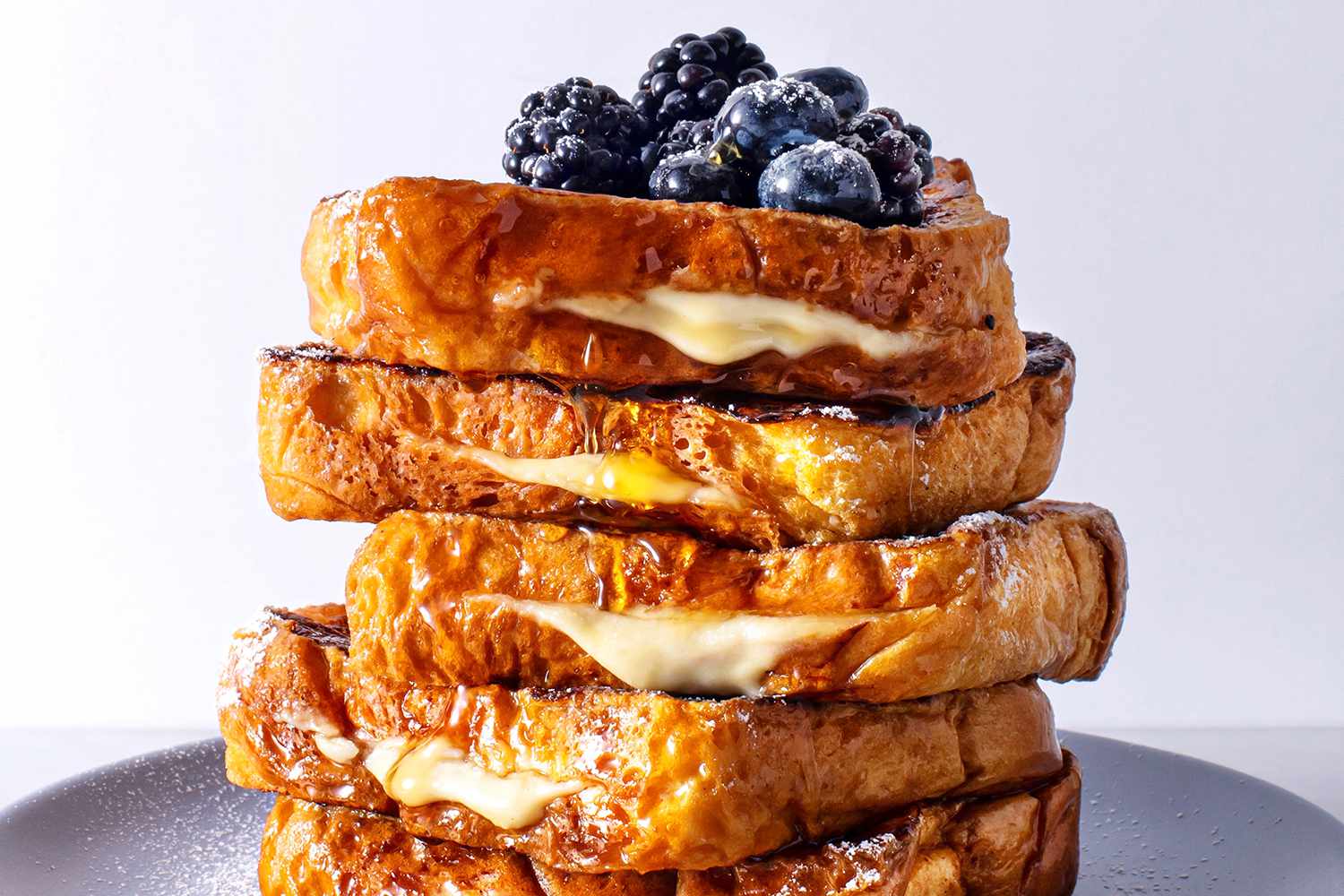 Stack of stuffed french toast with blueberries and blackberries on a plate.