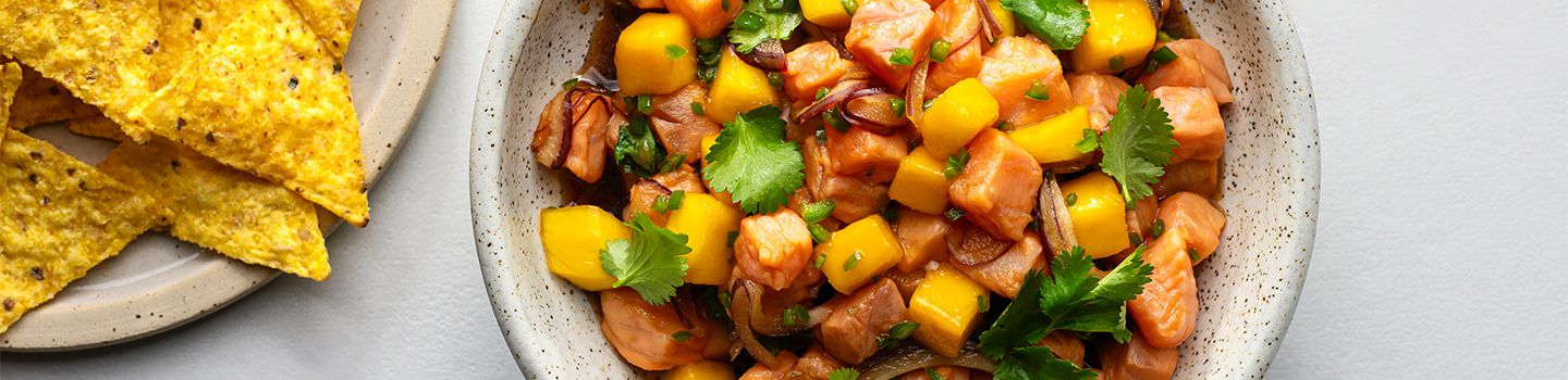 Bowl of salmon ceviche with mango served with tortilla chips