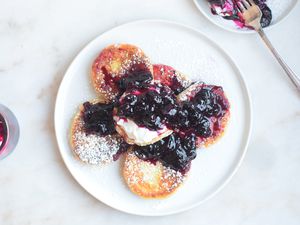 syrniki served with blueberry preserves and sour cream on a plate