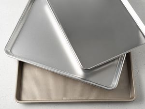 Assortment of baking sheets we recommend layered on top of each other displayed on a white surface