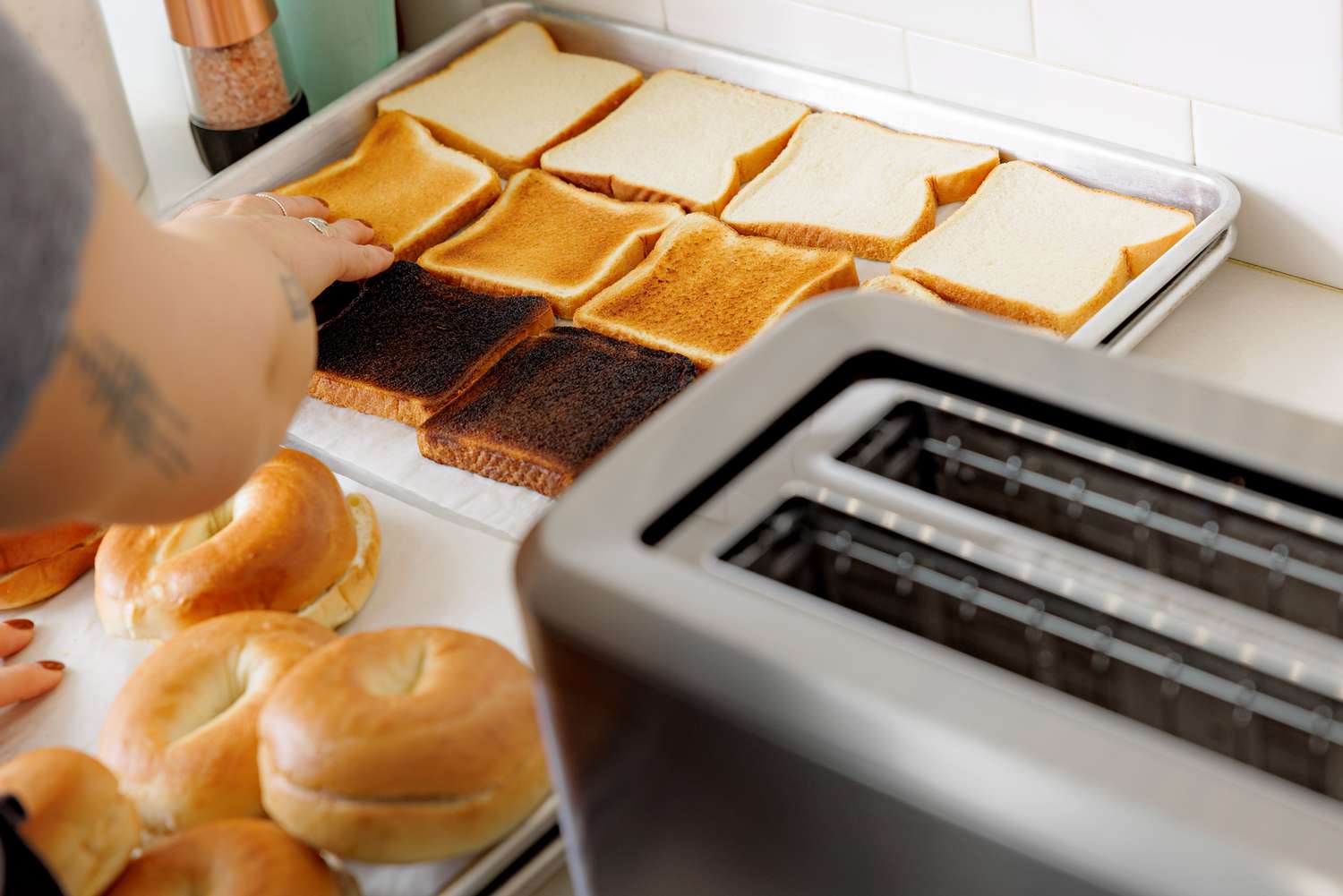 Breville BTA720XL Bit More Toaster next to bread slices and bagels of different shades