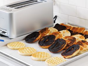 Tray of toasted food next to the Breville BTA820XL Die-Cast 2-Slice Smart Toaster