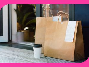 A photo of two brown paper takeout bags with receipts stapled to them sitting on someone's front porch