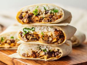 Three vegetarian bean and rice burritos stacked on top of each other 